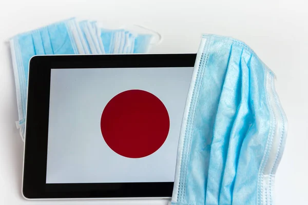 Japan flag covered by surgical protective mask for coronavirus COVID-19 prevention, San Francisco, USA. April 2020