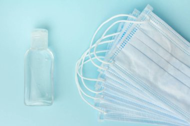 Antibakteriyel alkol jeli ve mavi arka planda koronavirüsü önlemek için cerrahi koruyucu maskeler. Salgın ve karantina süresince sağlık konsepti.