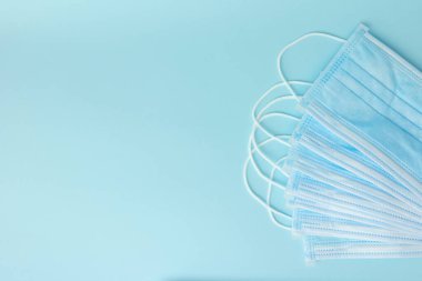 Mavi arka planda Coronavirus önleme için yeni cerrahi maskeler. Sağlık sigortası konsepti. Tıbbi araçlar