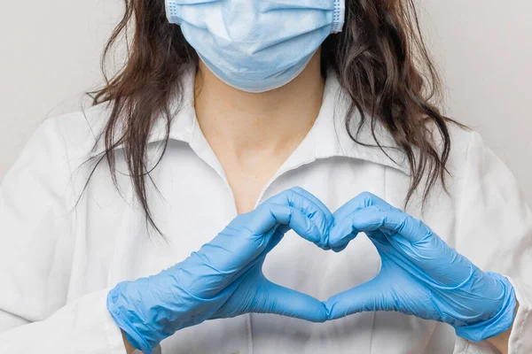 Stop SARSCoV, virus 2020 , MERS-CoV, chinese virus COVID-19. Womens hand in blue medical gloves show heart sign. Concept of protection against HIV. Doctor in blue medical gloves and protective mask