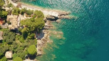 Turkuvaz mavisi yeşil suyla yıkanan kayalık deniz kıyısına iniyorlar. Ligurian Denizi 'nin altında büyük taşlar, Camogli, İtalya.