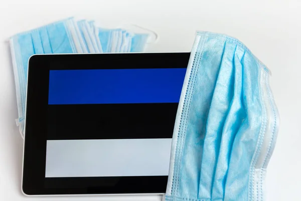 Bandera de Estonia cubierta por máscara protectora quirúrgica para coronavirus COVID-19 prevención . —  Fotos de Stock