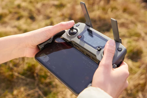 Närbild kvinnors händer håller en fjärrkontroll med en smartphone. Begreppet flygbilder, San Francisco, maj 2020 — Stockfoto