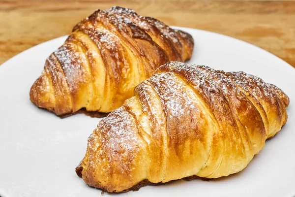 Close up two freshly baked croissants with sugar powder on a white plate. Puff french pastry. — Stock Photo, Image