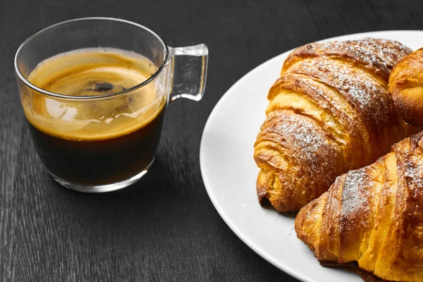 커피 한잔 과 갓 구운 크로와 상을 어두운 탁자 위에 놓고 먹는다. 아침 식사 컨셉트를 제공 합니다. 퍼프 반죽으로 만든 프랑스어 페이스트리 — 스톡 사진
