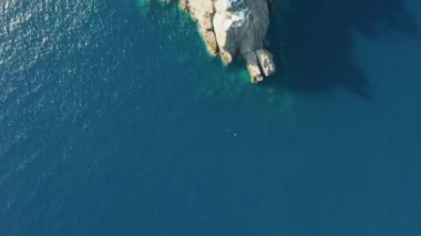 Ligurian Denizi 'ndeki kayalık bir tepenin üzerinde mavi turkuaz su ve dipte kocaman taşlarla uçarken Portofino, İtalya. 