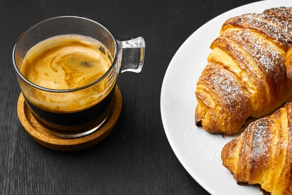 一杯咖啡和新鲜烤的羊角面包放在黑暗的桌子上 服务早餐的概念 法式糕点 用膨脂面团制成 — 图库照片