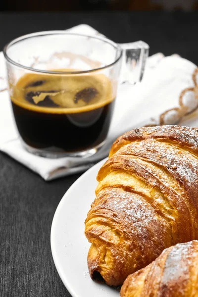 Croissants au beurre et une tasse de café sur fond noir. Cuisson maison — Photo