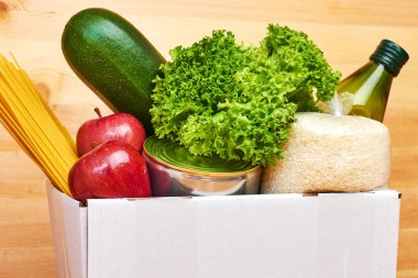 Tahta arka planda farklı sağlıklı ürünlerin olduğu beyaz kutuyu kapat. Süpermarketten ya da internetten yiyecek teslimatı hizmeti