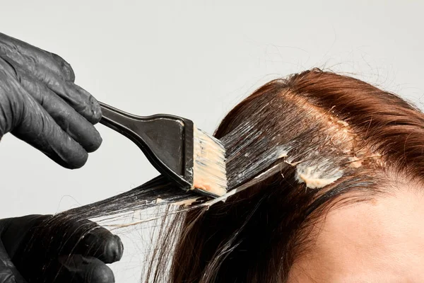 En frisör som färgar håret till kvinnor med svart borste. Brunett byter hårfärg. Maken färgar håret till sin fru. — Stockfoto
