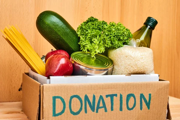 Caja de cartón de donación con varios alimentos, verduras, frutas, cereales, aceite y alimentos enlatados. Concepto de caridad o entrega . — Foto de Stock