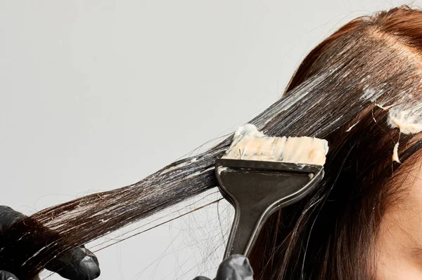 Ein Friseur färbt Frauen mit einem schwarzen Pinsel die Haare. Brunet ändert eine Haarfarbe. — Stockfoto