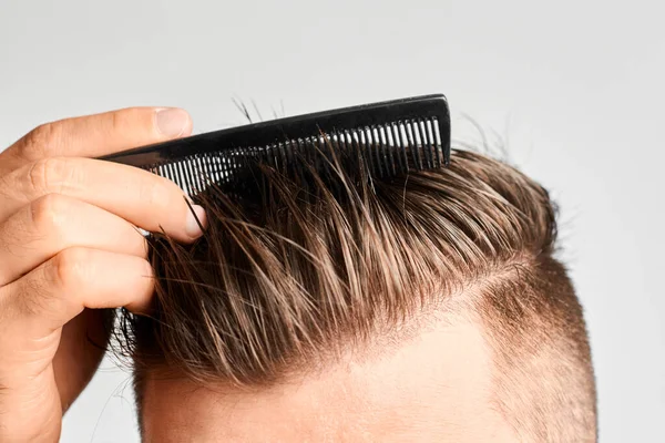 Mann kämmt sein sauberes Haar mit einem Plastikkamm. Haarstyling zu Hause. Konzept von Haarausfall oder Schuppen — Stockfoto