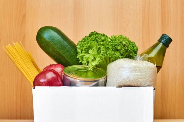 Tahta arka planda farklı sağlıklı ürünlerin olduğu beyaz kutuyu kapat. Süpermarketten ya da internetten yiyecek teslimatı hizmeti