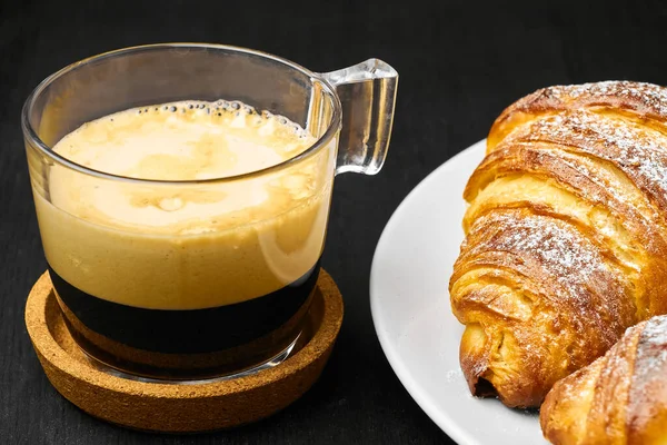 Kaffee und frisch gebackene Croissants auf einem dunklen Tisch. Frühstückskonzept serviert. Französisches Gebäck aus Blätterteig — Stockfoto