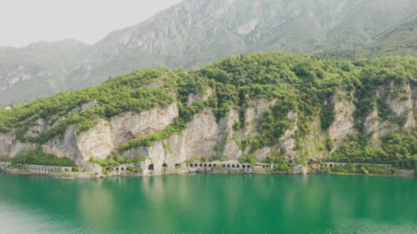 Luchtopname van het naderen van de tunnel in de berg omgeven door groen water van Como Lake, Lecco, Italië. — Stockvideo