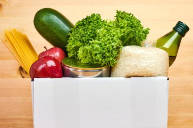 Tahta arka planda farklı sağlıklı ürünlerin olduğu beyaz kutuyu kapat. Süpermarketten ya da internetten yiyecek teslimatı hizmeti