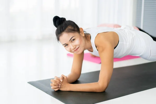 Healthy Asian ethnicity sport woman doing exercise in a gym. Happy Asian woman posing in perfect plank exercise . Wellness, wellbeing and spiritual lifestyle in adult people concept.