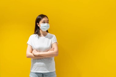 Grip ve virüsü korumak için yüzüne koruyucu hijyen maskesi takan Asyalı genç çekici bir kadın. Hasta kadın portresi ve sarı arkaplan nezlesi. Covid19 ve Coronavirus.