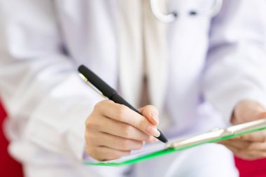 Doktor, hastanedeki panodan tıbbi belgelerin listesini kontrol ediyor. Tıbbi muayene ve teşhis sonucu belgesi panoda. Modern yaşam tarzı konsepti ve eşmekanında sağlık hizmetleri.