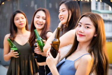 Partide beyaz şarap ve birayla kutlama yapan bir grup insan. Mutlu Asyalılar festivalde eğlenmeyi ve çatıdaki barda ve restoranda beyaz şarapla kutlamayı severler..
