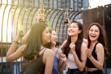 Partide beyaz şarap ve birayla kutlama yapan bir grup insan. Mutlu Asyalılar festivalde eğlenmeyi ve çatıdaki barda ve restoranda beyaz şarapla kutlamayı severler..