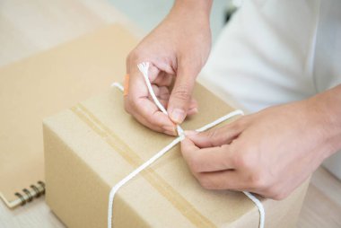 Güzel Asyalı kadın masaya bir posta paketi koyuyor, online alışveriş ve e-ticaret küçük işletme konseptinde..