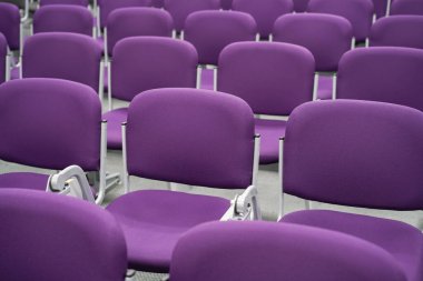 Havaalanından kalkış için bekleme alanındaki boş koltuklar. Havaalanı terminalinde mor koltuklar.