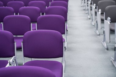 Havaalanından kalkış için bekleme alanındaki boş koltuklar. Havaalanı terminalinde mor koltuklar.