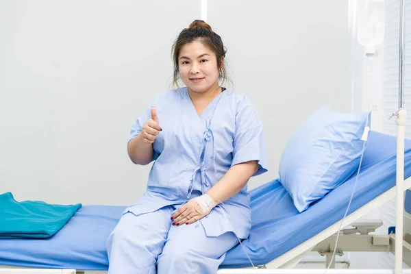 Asian patient fat woman sitting on the bed in hospital close up.