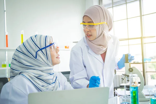 2人のイスラム教徒の女性化学者が実験室で実験を — ストック写真