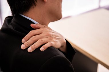 Asyalı yaşlı iş adamı çok çalışmaktan ofis sendromu sorunu yaşıyor. Çalışan insanlarda sağlık ve iş hayatı dengesi kavramı.