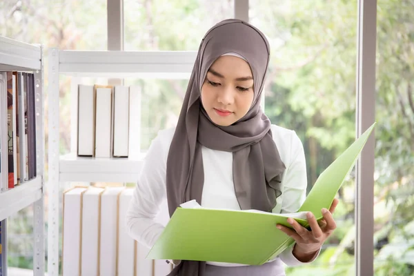 アジア系ムスリムビジネスウーマンオフィスの本棚で本を選ぶムスリム女性学生 — ストック写真