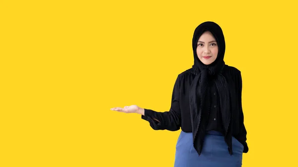 明るい黄色の背景にポーズをとり 左手を見せるアジア系ムスリム女性学生 成功したアジアのイスラム教徒の女性の概念とコピースペースと多様な民族の概念 — ストック写真