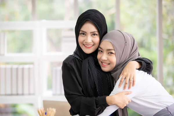 Smart and beautiful Asian muslim business people expressing happy emotion together in meeting room. Asian Muslim business women in smart casual shirt. Business deal and discussion concept.