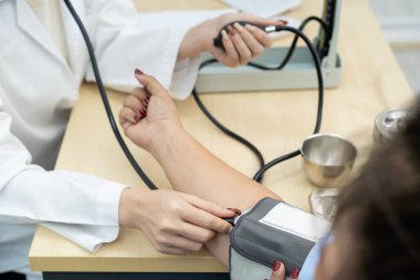 Asyalı kadın doktor hastanede obez kadının tansiyonunu ölçüyor. Sağlıksız beslenme davranışları yüzünden aşırı kilo ve obezite hastalığı. Şişman Asyalı kadın hasta danışmanlığı.