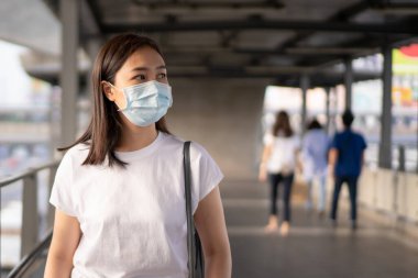 Kalabalık yerlerde dolaşırken COVID19 virüsünü ve PM2.5 kirliliğini korumak için hijyen koruyucu maske takan bir kadın. Kadın Asya ülkesindeki Corona virüsünü korumak için yüz maskesi kullanıyor. Hastalık.