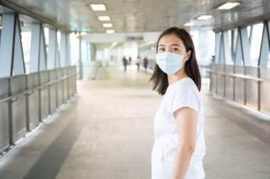 COVID19 virüsünü, COVID-19 'u ve PM2.5' u korumak için hijyen koruyucu maske takan bir kadın kalabalık bir yerde seyahat ediyor. Kadın, koronavirüs hastalığını korumak için yüz maskesi kullanıyor. 2019-nCov krizi.