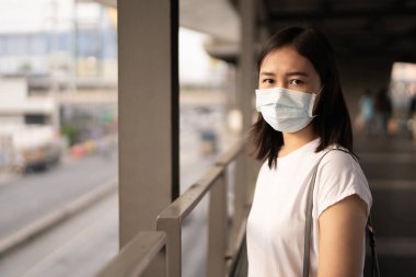 COVID19 virüsünü, COVID-19 'u ve PM2.5' u korumak için hijyen koruyucu maske takan bir kadın kalabalık bir yerde seyahat ediyor. Kadın, koronavirüs hastalığını korumak için yüz maskesi kullanıyor. 2019-nCov krizi.