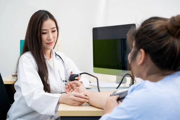 Asian woman doctor checking obese woman\'s blood pressure at doctor\'s office in hospital. Overweight and obesity sickness from unhealthy eating behavior. Overweight Asian woman patient consults doctor.