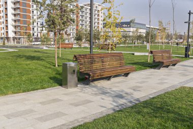 Şehir parkındaki ahşap bir bankın yakınında. Yürüyüş sırasında dinlenin. Temizlik, temizlik ve doğa için bakım..