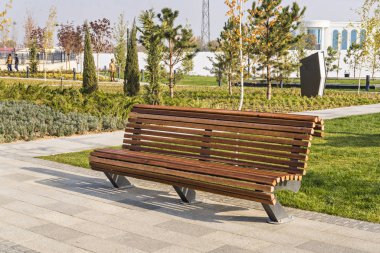 Şehir parkındaki ahşap bir bankın yakınında. Yürüyüş sırasında dinlenin. Temizlik, temizlik ve doğa için bakım..