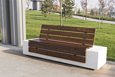 Şehir parkındaki ahşap bir bankın yakınında. Yürüyüş sırasında dinlenin. Temizlik, temizlik ve doğa için bakım..