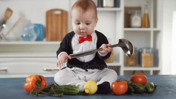 Детский повар сидит с ковшем и овощами — стоковое видео