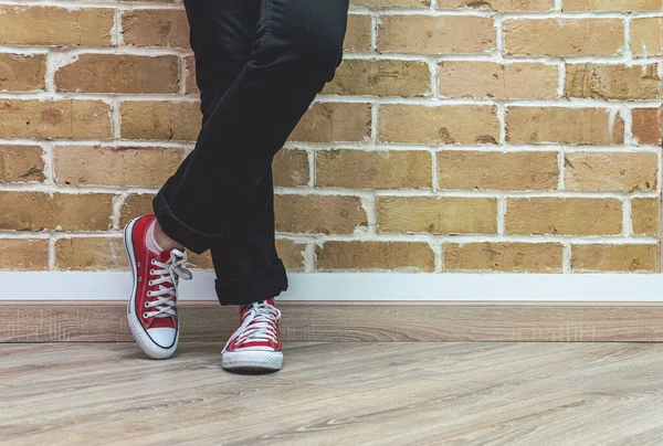 Kot pantolon ve kırmızı spor ayakkabılı kadın bacakları. — Stok fotoğraf