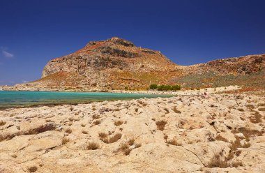 2019, 4 Haziran: - GREECE, CRETE Adası, GramvOUSA - Dağın tepesindeki kale ve altındaki plajdaki insanlar.