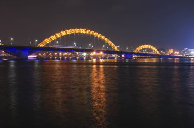 Gece Da Nang 'daki sarı ışıklı Ejderha Köprüsü Han Nehri, Vietnam' a yansıdı. 