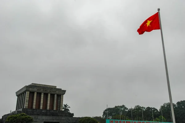 Ho Chi Minh Mausoleum on Ba Dinh Square in Hanoi with Vietnamese flag waving in the wind, Vietnam