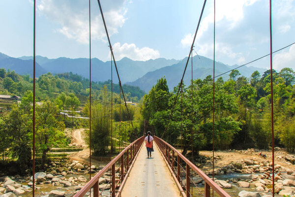 A Hmong girl walking on a bridge across stream in Sapa, Vietnam 