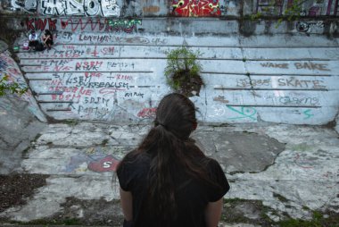 Prag, Barrandov Teraslarında terk edilmiş ve çürümüş bir yüzme havuzunun kenarında oturan bir kız.